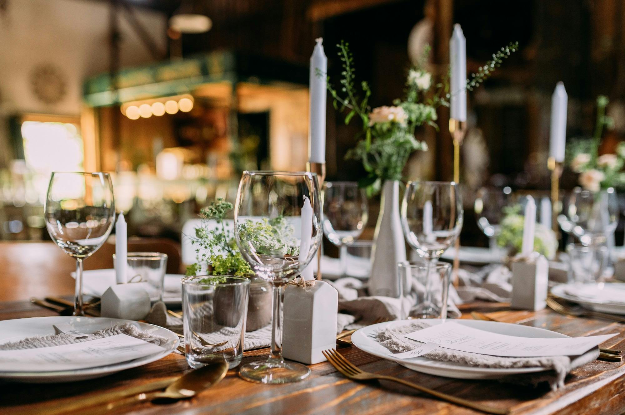 Elegante Tischdekoration für ein Event mit Kristallgläsern, weißen Kerzen und Blumenschmuck.